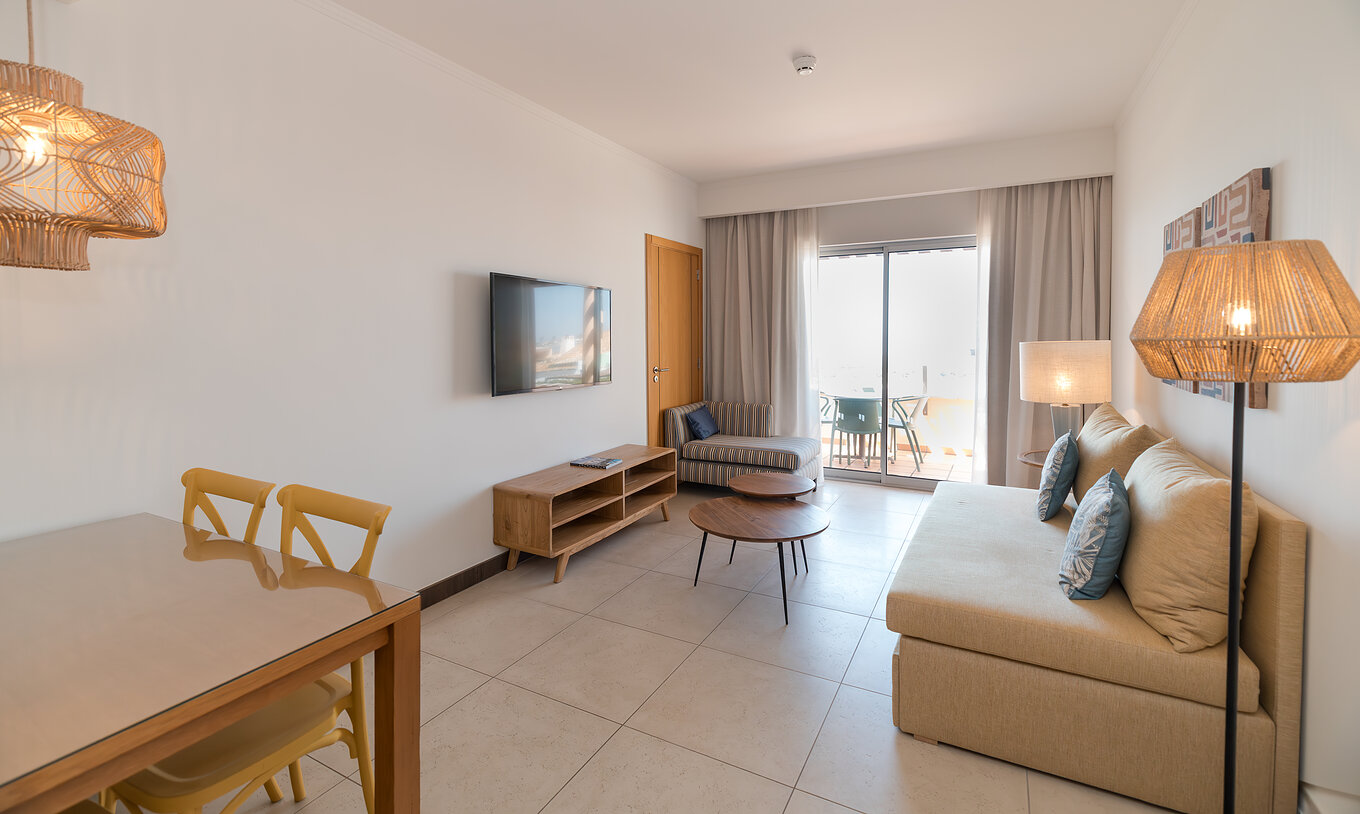 O Apartamento T1 Vista Mar do Pestana Alvor Beach Villas tem uma sala com sofá, televisão, e uma janela com acesso à varanda