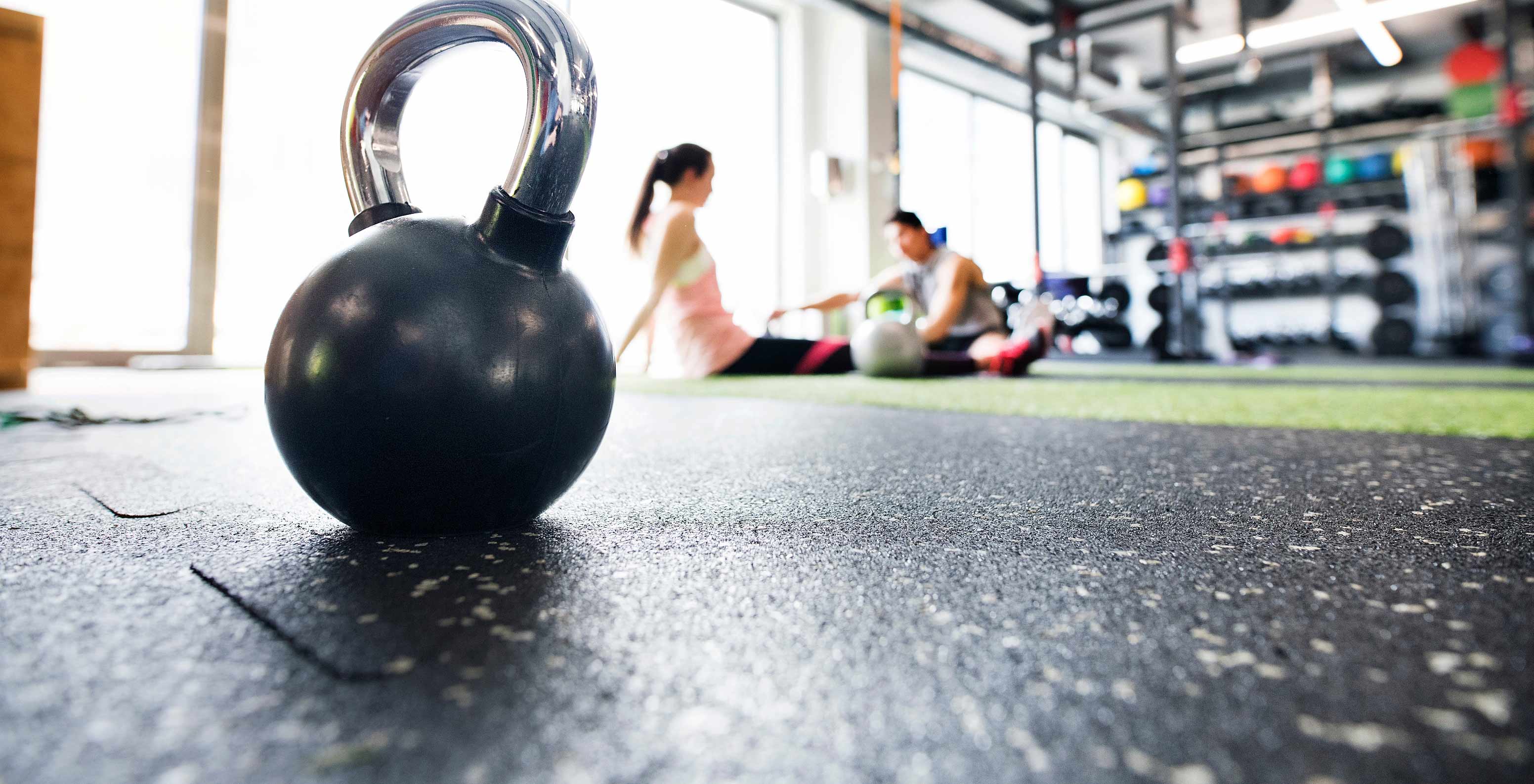 Foco num kettlebell, com hóspedes a treinar no ginásio do Pestana Alvor Park, Aparthotel 4 Estrelas no Alvor com Piscina