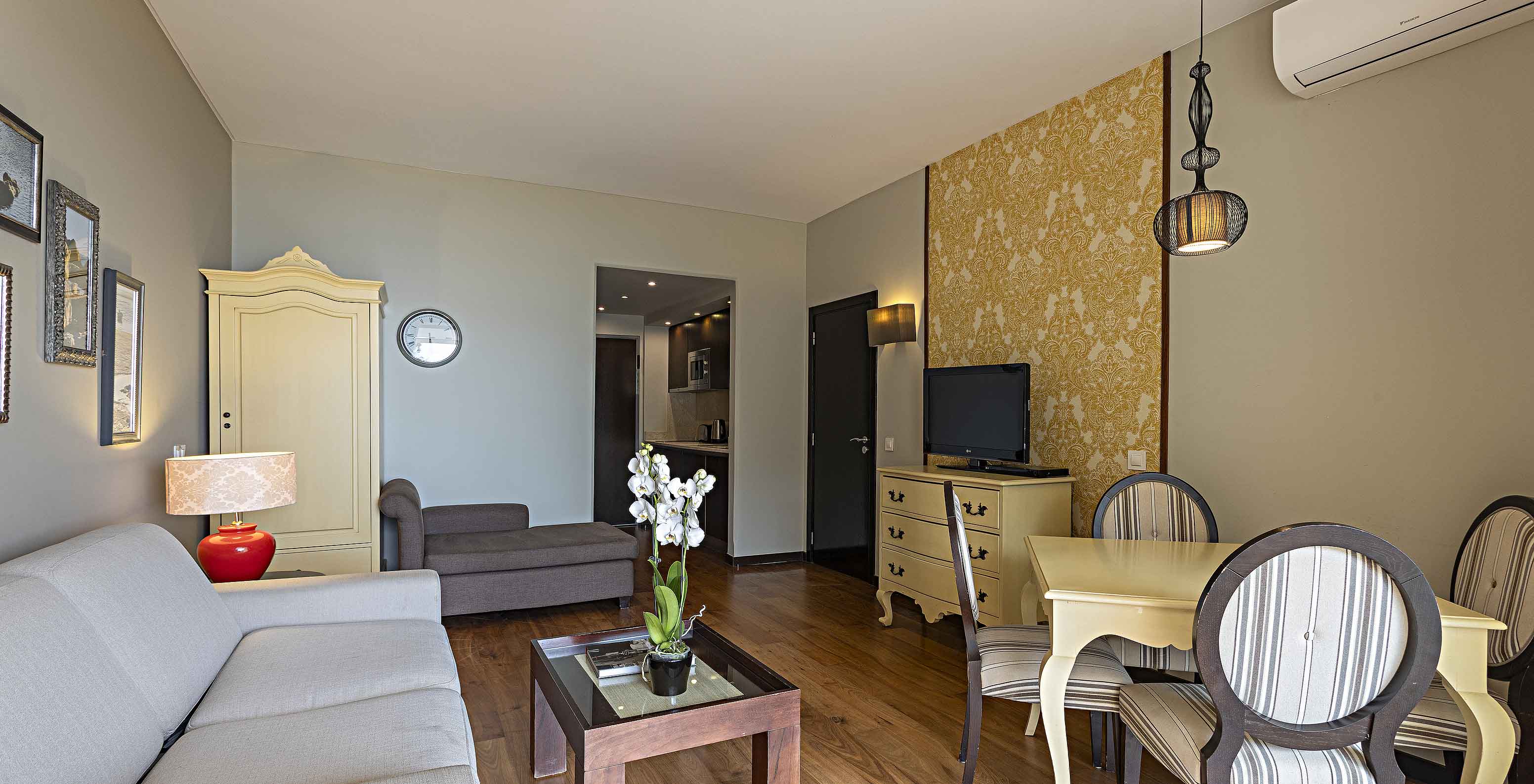 A Cliff Suite T1 do Pestana Alvor Praia tem uma sala de estar com um sofá, papel de parede, televisão e uma mesa de jantar