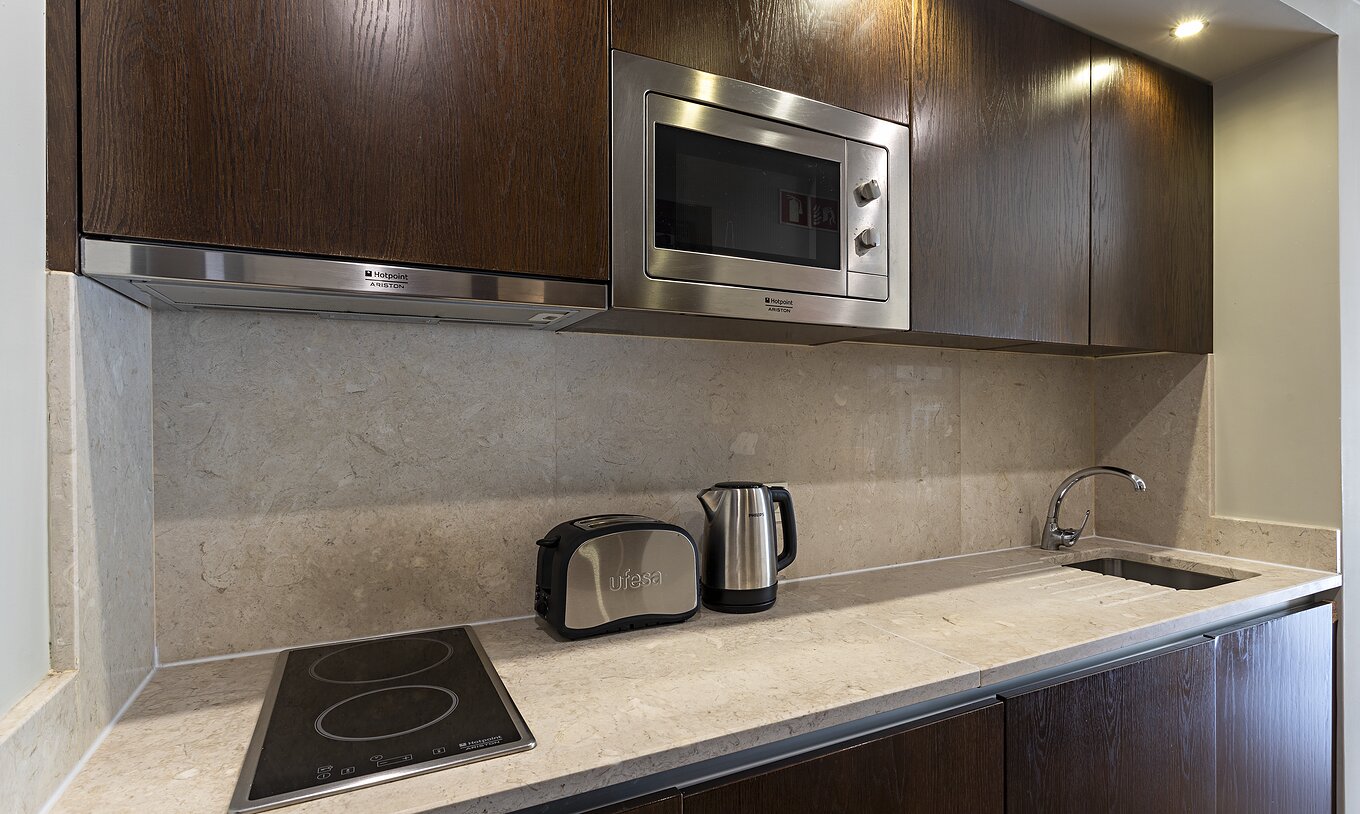 A Cliff Studio do Pestana Alvor Praia tem uma cozinha de madeira escura e um balcão em pedra, com um fogão e um micro-ondas