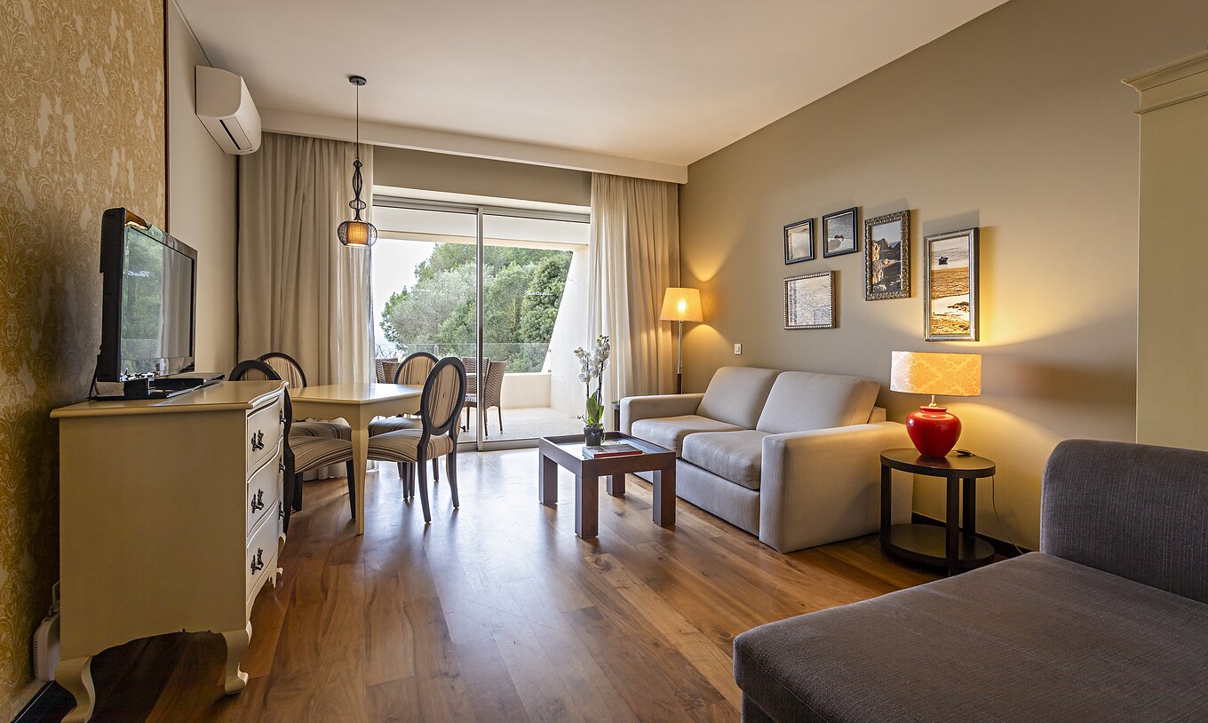 A Cliff Suite T1 do Pestana Alvor Praia tem uma sala com dois sofás, uma cómoda com televisão, uma mesa de jantar e cadeiras