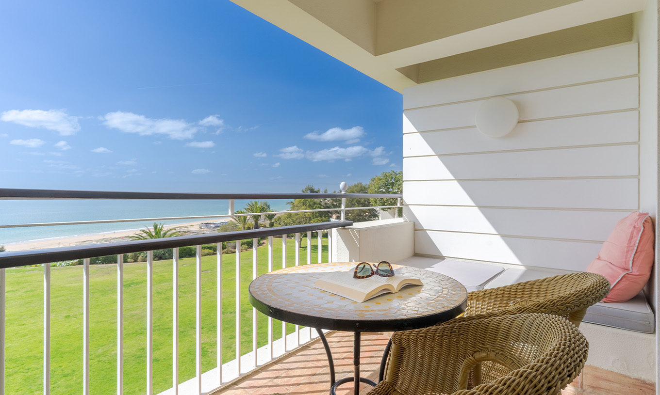 O Deluxe Vista Mar do Pestana Alvor Praia tem varanda com cadeiras, mesa e sofá com vista para o mar, praia e jardim do hotel