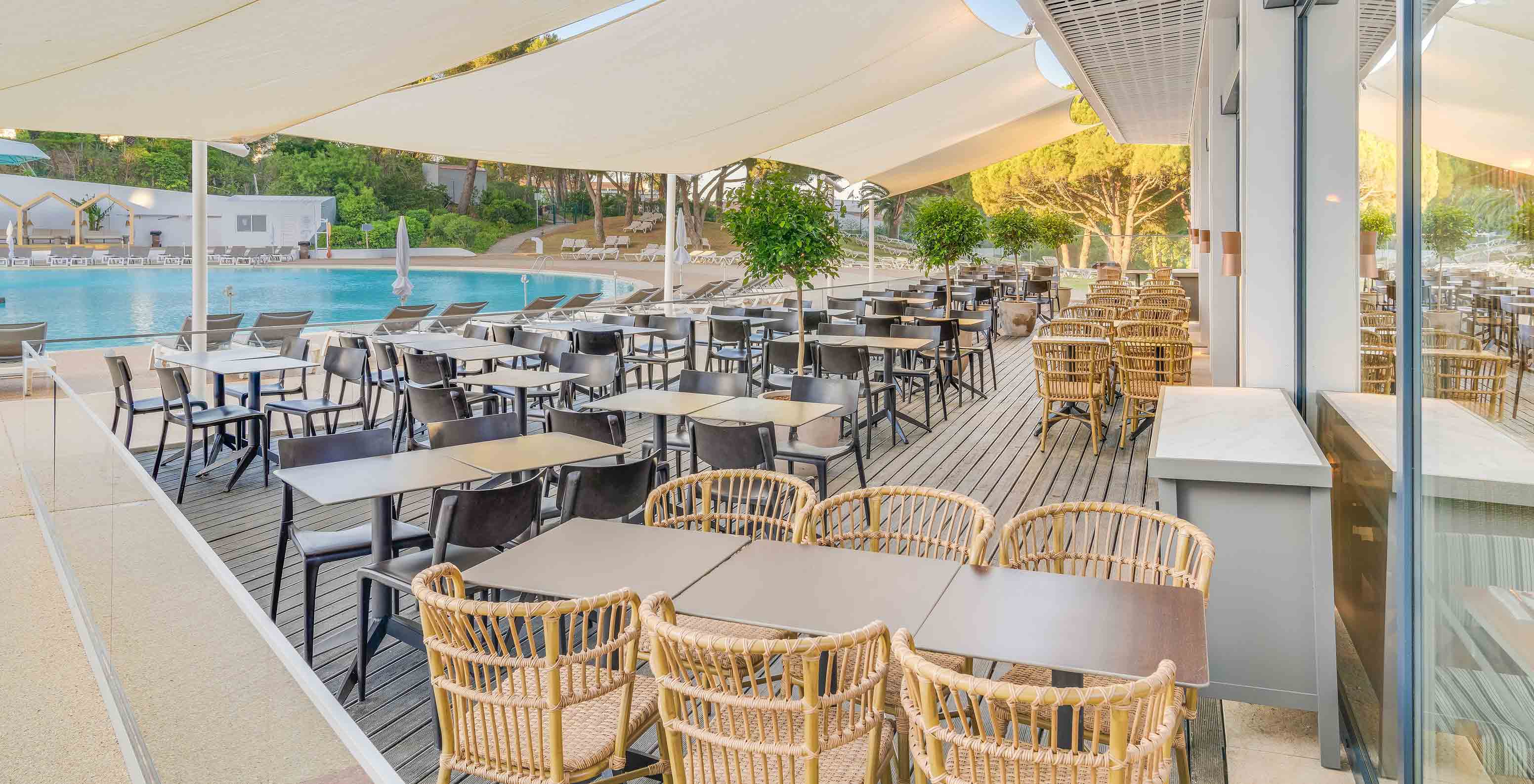 O bar Acqua, do Hotel Tudo Incluído no Algarve, tem mesas e cadeiras no exterior junto à piscina.