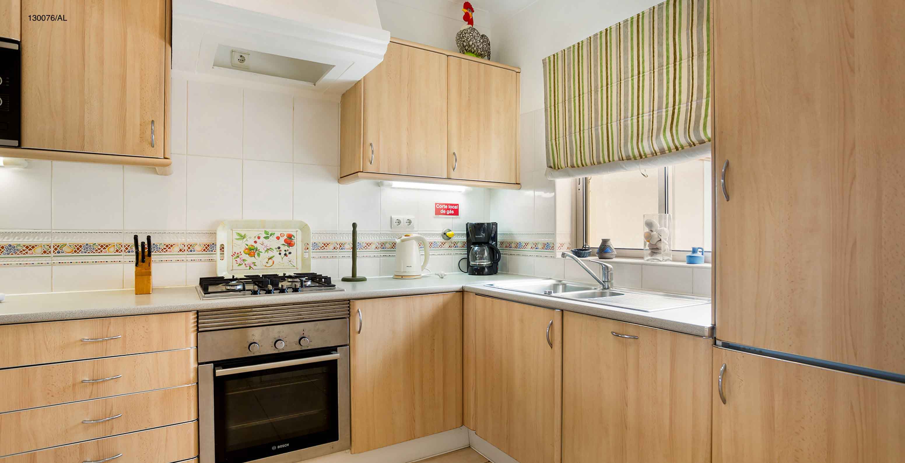 O Apartamento T2 Standard do Pestana Carvoeiro Golfe tem uma cozinha equipada com armários de madeira e eletrodomésticos