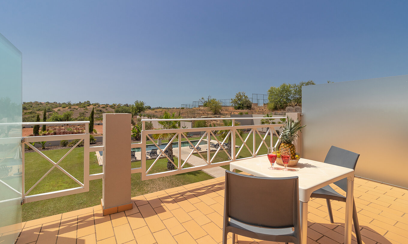 O Quarto Clássico - Vista Piscina do Pestana Gramacho Residences tem varanda com mesa e vista para piscina e área verde.