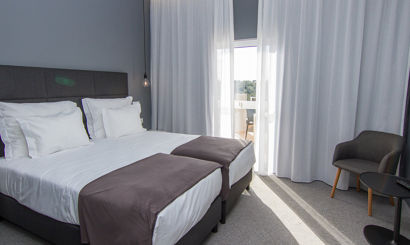 O Quarto Clássico Vista Piscina do Pestana Gramacho Residences tem duas camas individuais, uma cadeira e uma janela