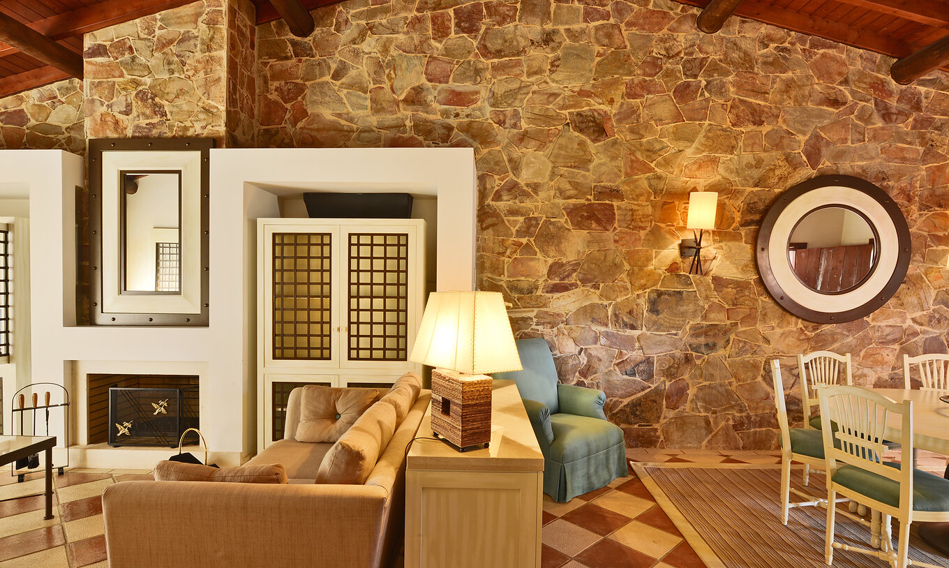 A Suite Vista Jardim Vila Sol do Pestana Vila Sol - Vilamoura tem uma sala com um sofá, lareira e mesa para refeições 