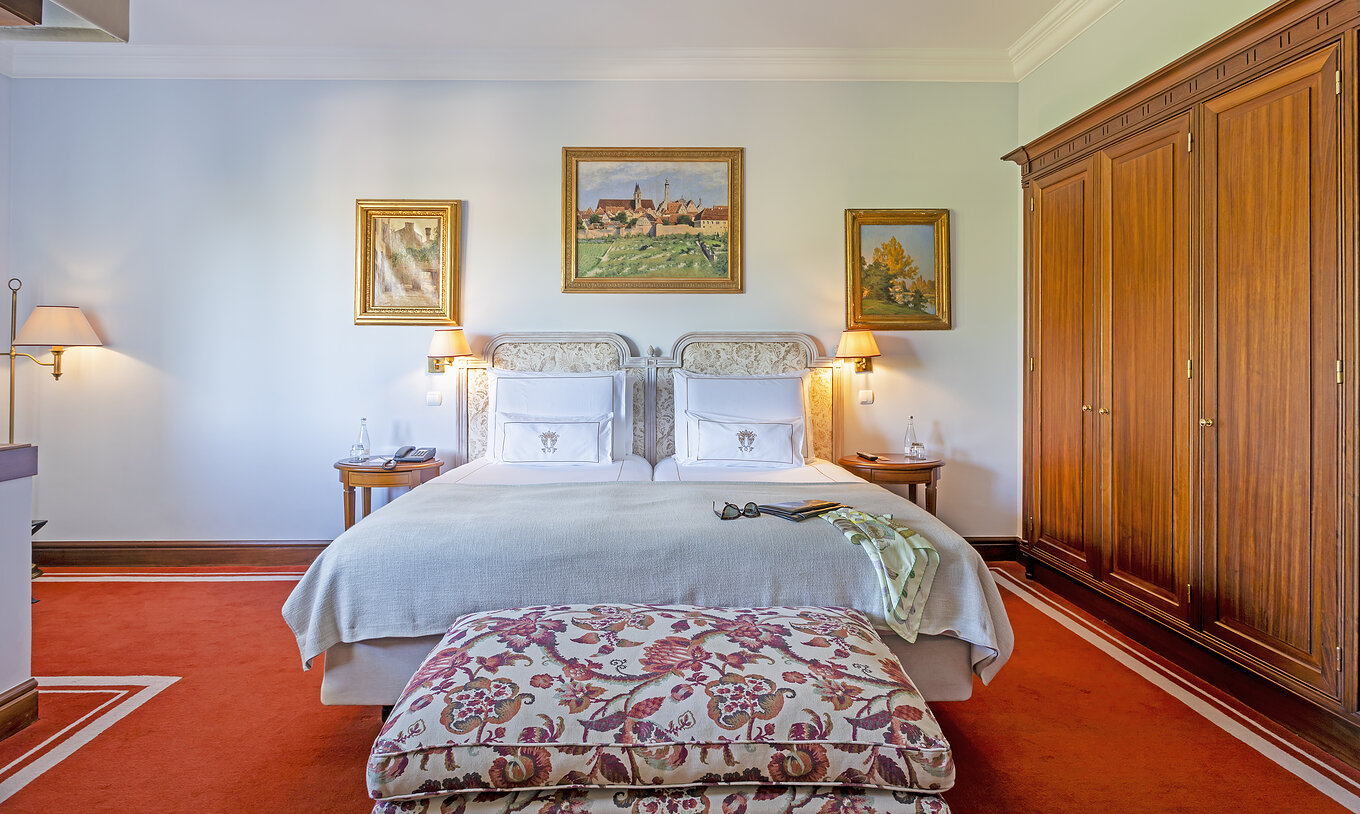 A Suite do Pestana Palace Lisboa tem uma cama de casal com uma banqueta nos pés da cama e um armário grande