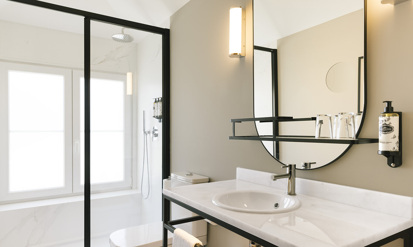 A Junior Suite do Pestana Rua Augusta Lisboa tem uma casa de banho com lavatório em mármore branco, espelho, sanita e duche