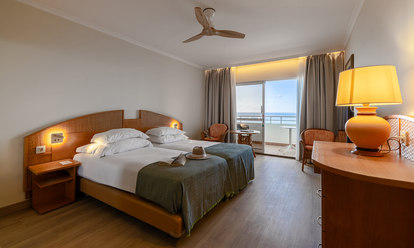 O Classic Sea View do Pestana Ocean Bay All Inclusive tem uma cama dupla, móvel TV, duas cadeiras e varanta com vista