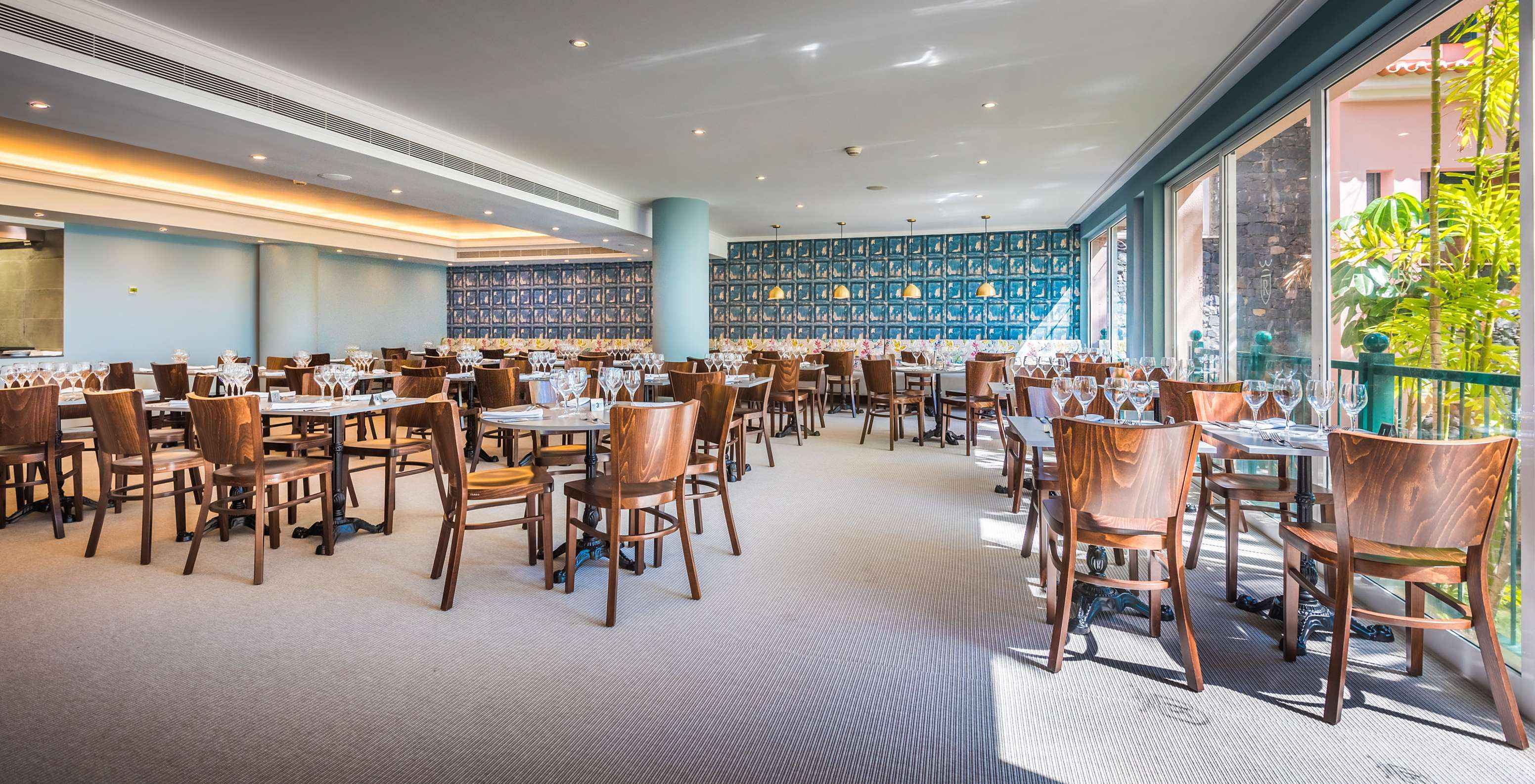 O restaurante Campo de Fiori, do Hotel 5 Estrelas com Tudo Incluído no Funchal, conta com mesas, cadeiras, e parede colorida