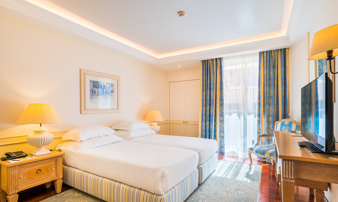 O quarto Deluxe com Varanda Vista Mar do Pestana Royal All Inclusive conta com duas camas individuais e mesa de cabeceira