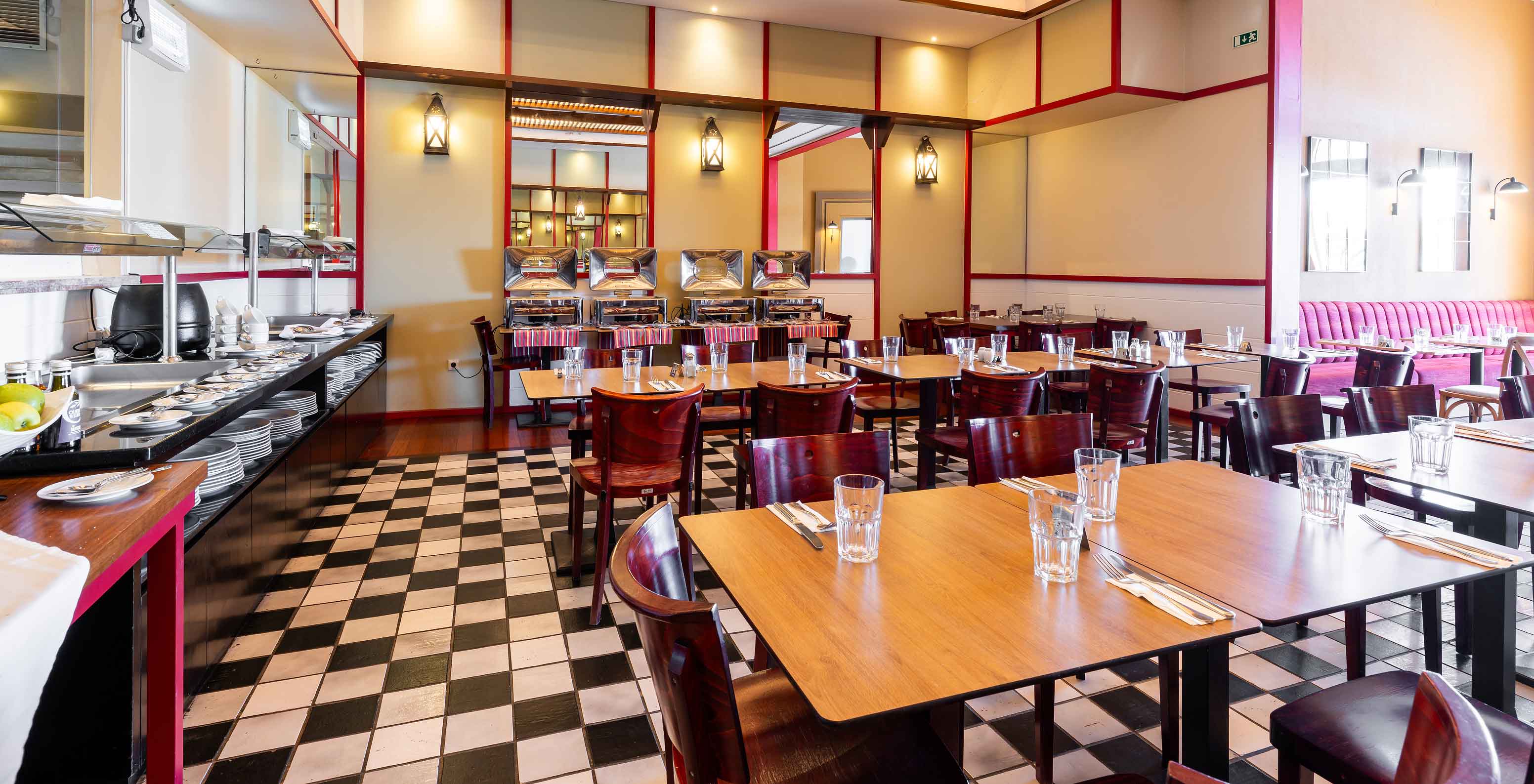 O restaurante Luigi, do Resort de 5 Estrelas no Porto Santo tem um chão com azulejos brancos e pretos e cadeiras escuras