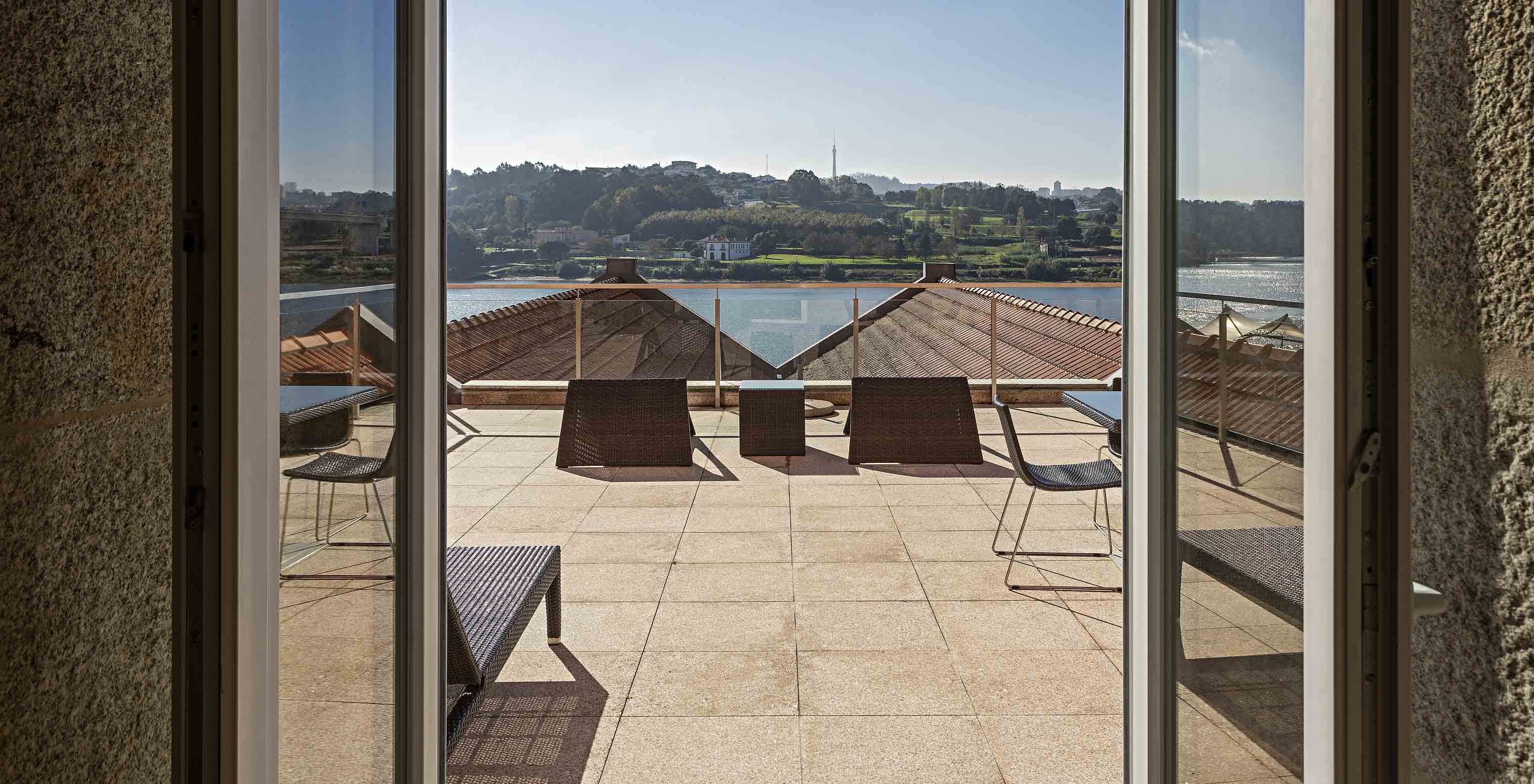 A Suite Nasoni do Pestana Palácio do Freixo tem uma varanda grande com duas mesas e cadiras e expreguiçadeira