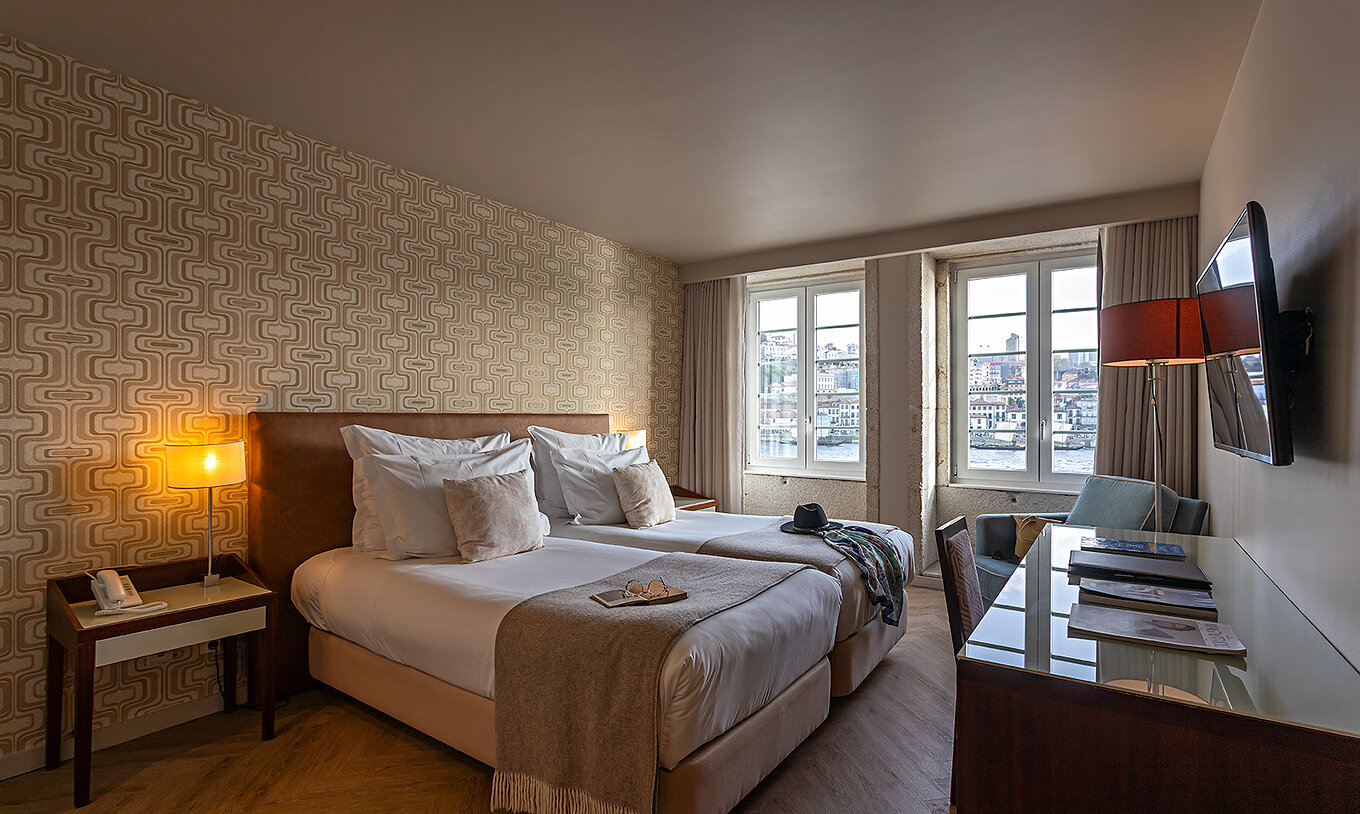 O Vintage River View do Pestana Vintage Porto tem duas camas individuais, papel de parede em tons areia e duas janelas