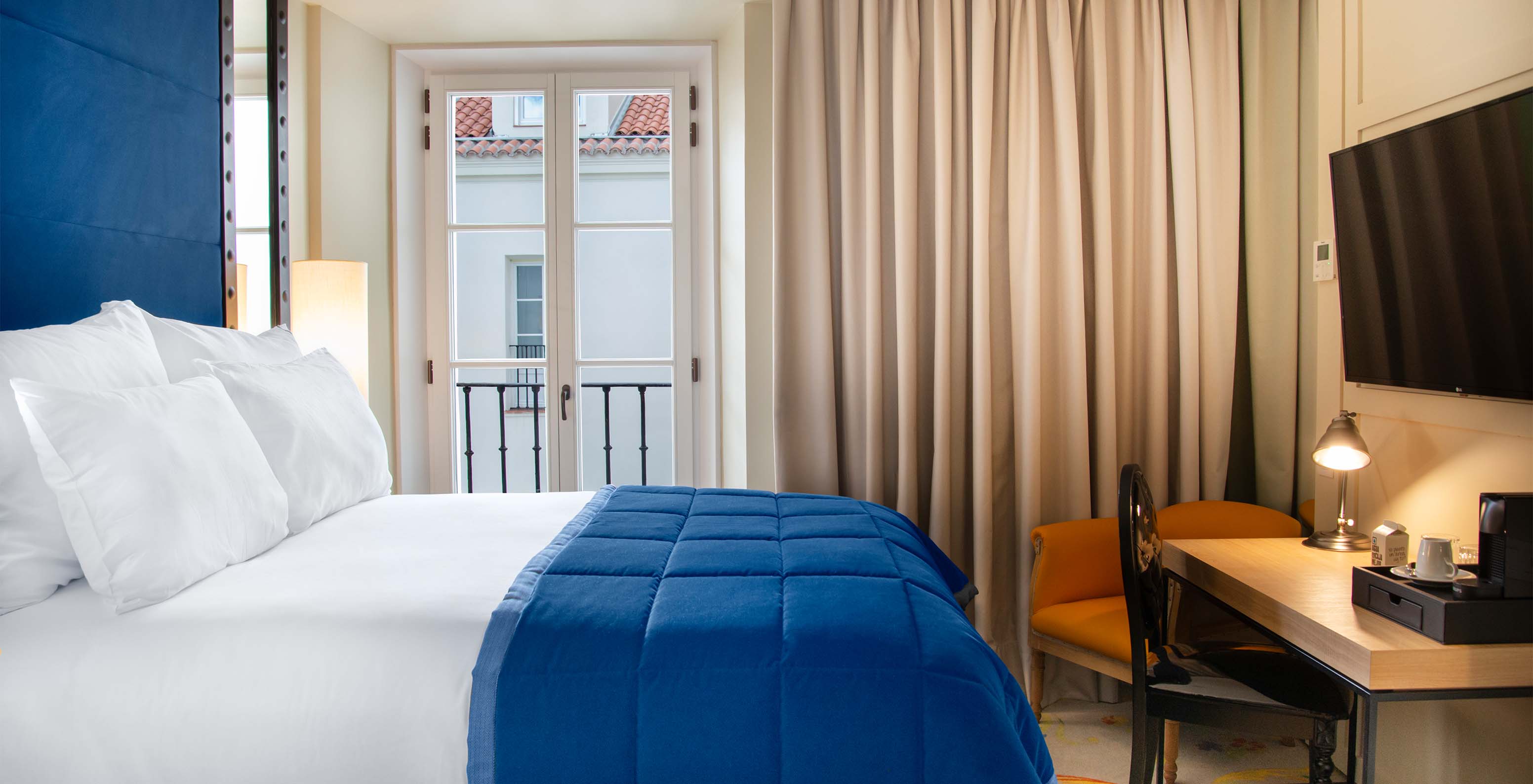 O Quarto Clássico do Pestana Collection Plaza Mayor tem uma cama de casal, televisão, secretária e uma janela com cortinas