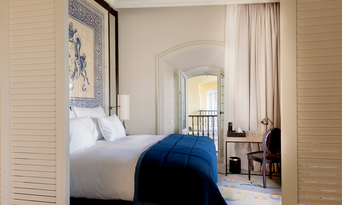 A Suite Plaza Mayor do Pestana Plaza Mayor Madrid tem uma cama de casal e uma cabeceira de cama com azulejos azuis e brancos