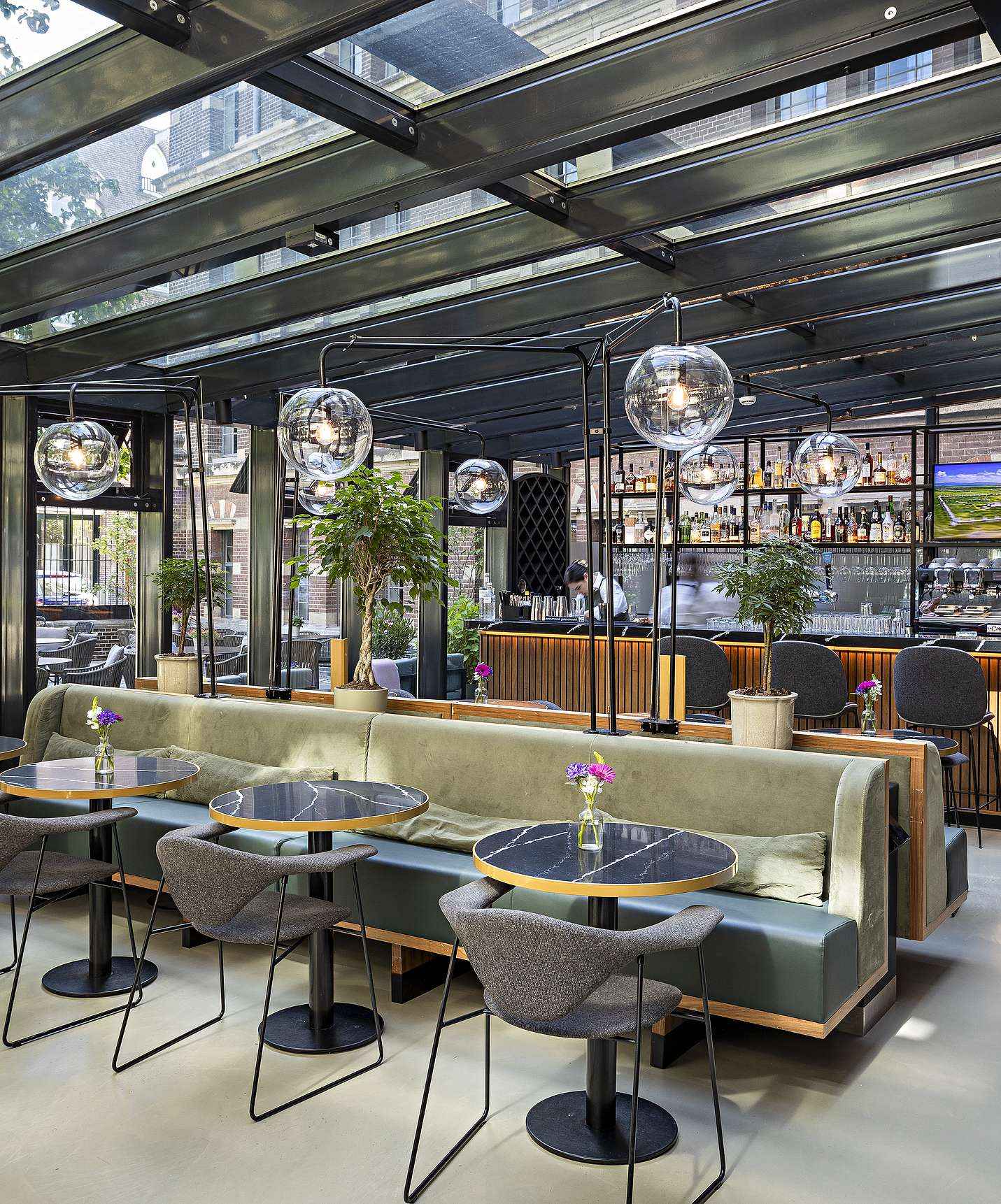 O Pestana Amsterdam Riverside, Hotel no Centro de Amesterdão, tem um restaurante amplo, com mesas e sofás, e paredes em vidro