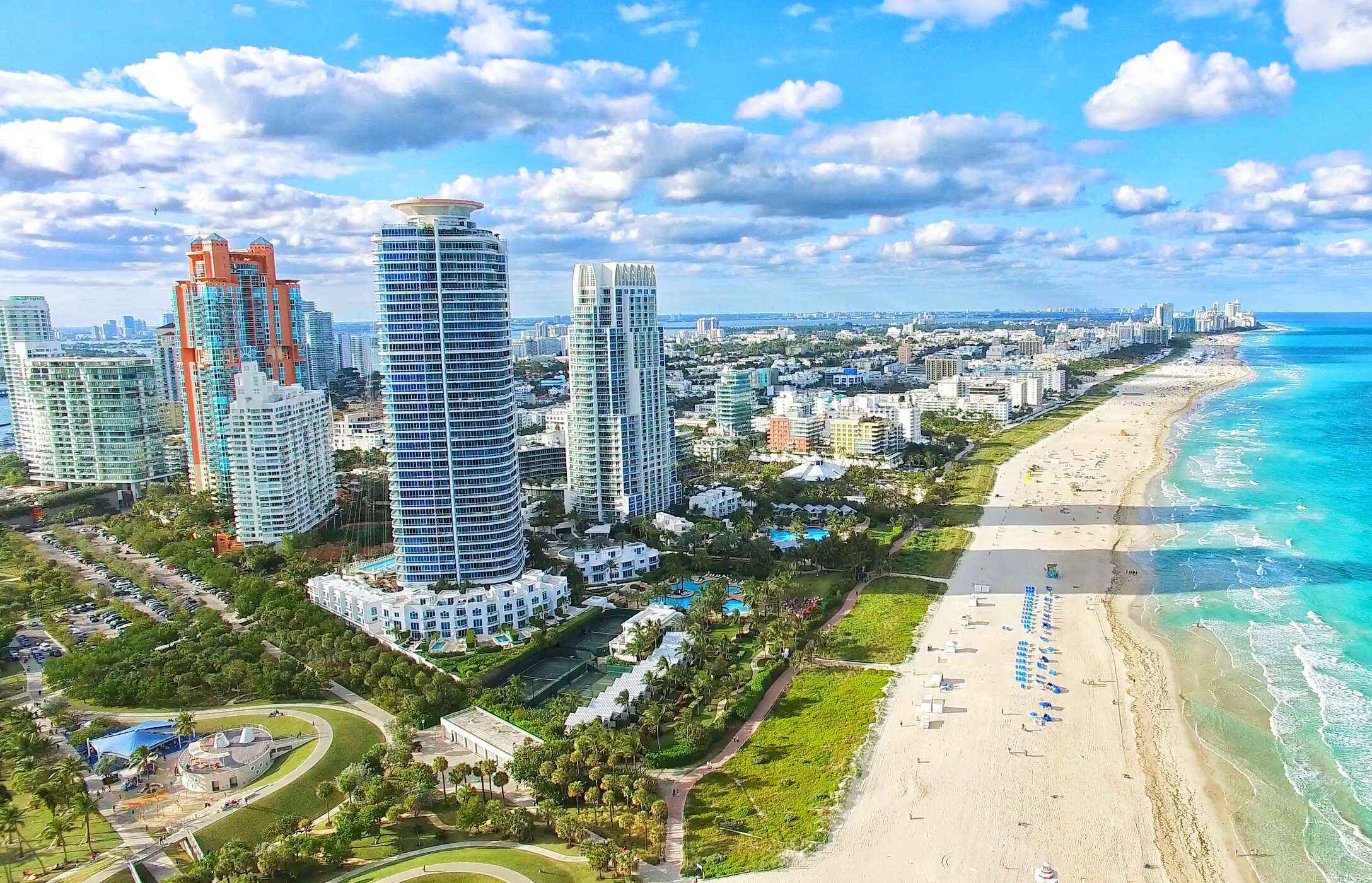 Vista sobre a praia de areia branca em South Beach, com águas cristalinas e edifícios altos paralelos à praia 