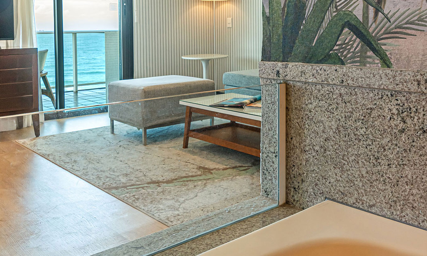 A Suite Frente Praia do Pestana Rio Atlântica tem uma sala com sofá, televisão e vista para o mar através da varanda