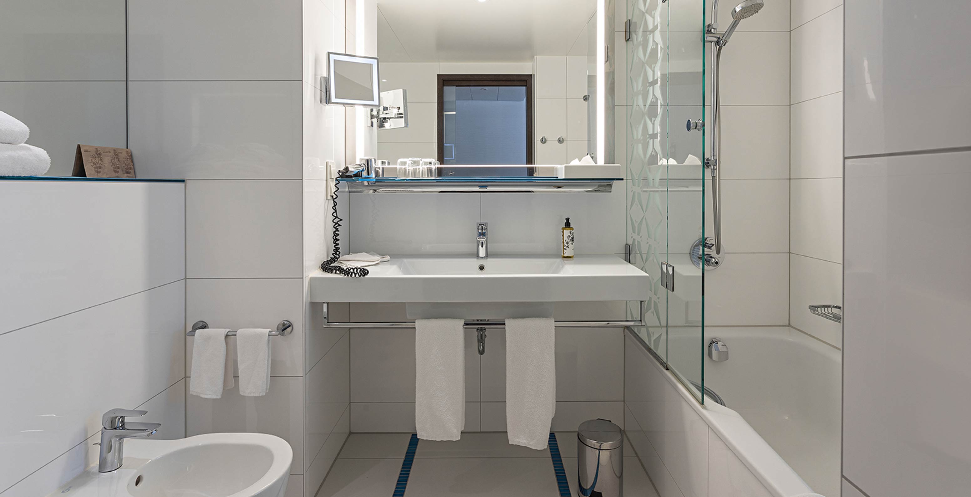 O Family Deluxe do Pestana Berlin Tiergarten tem uma casa de banho com banheira e duche, lavatório e espelho