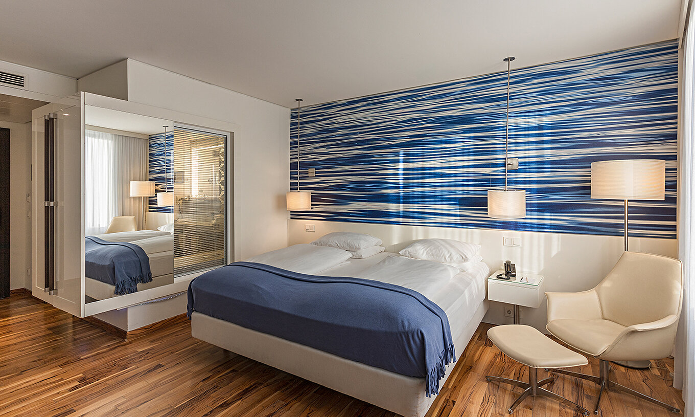 O Quarto Deluxe do Pestana Berlin Tiergarten conta com uma cama de casal, mesa de cabeceira com telefone, e um sofá