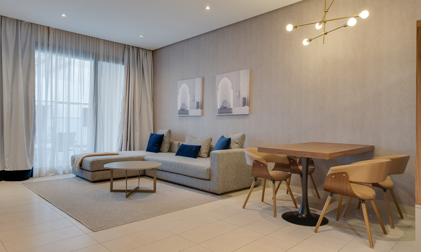 A Suite Familiar do Pestana Casablanca tem um sofá cinzento grande com chaise longue ao lado da janela