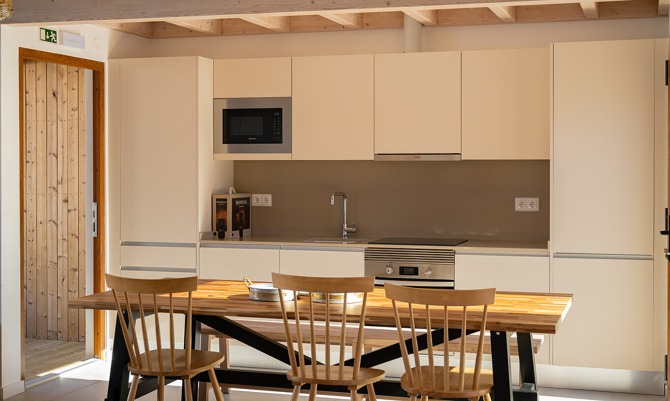 A Superior Villa do Pestana Comporta Village Residences tem uma cozinha moderna com uma mesa de madeira e forno