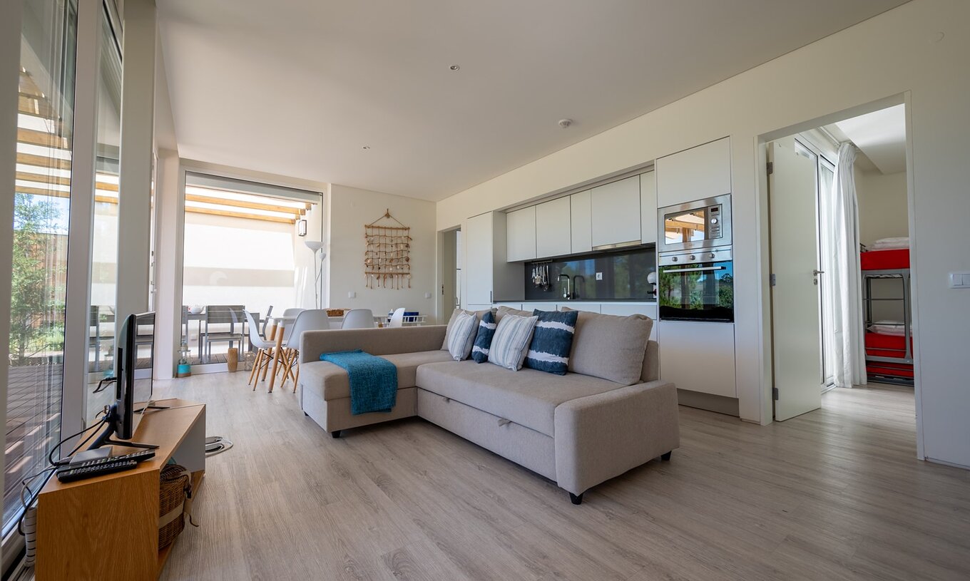 A Green Villa com Piscina Privada do Pestana Tróia Eco Resort tem uma sala junta com a cozinha, com sofá, mesa e televisão