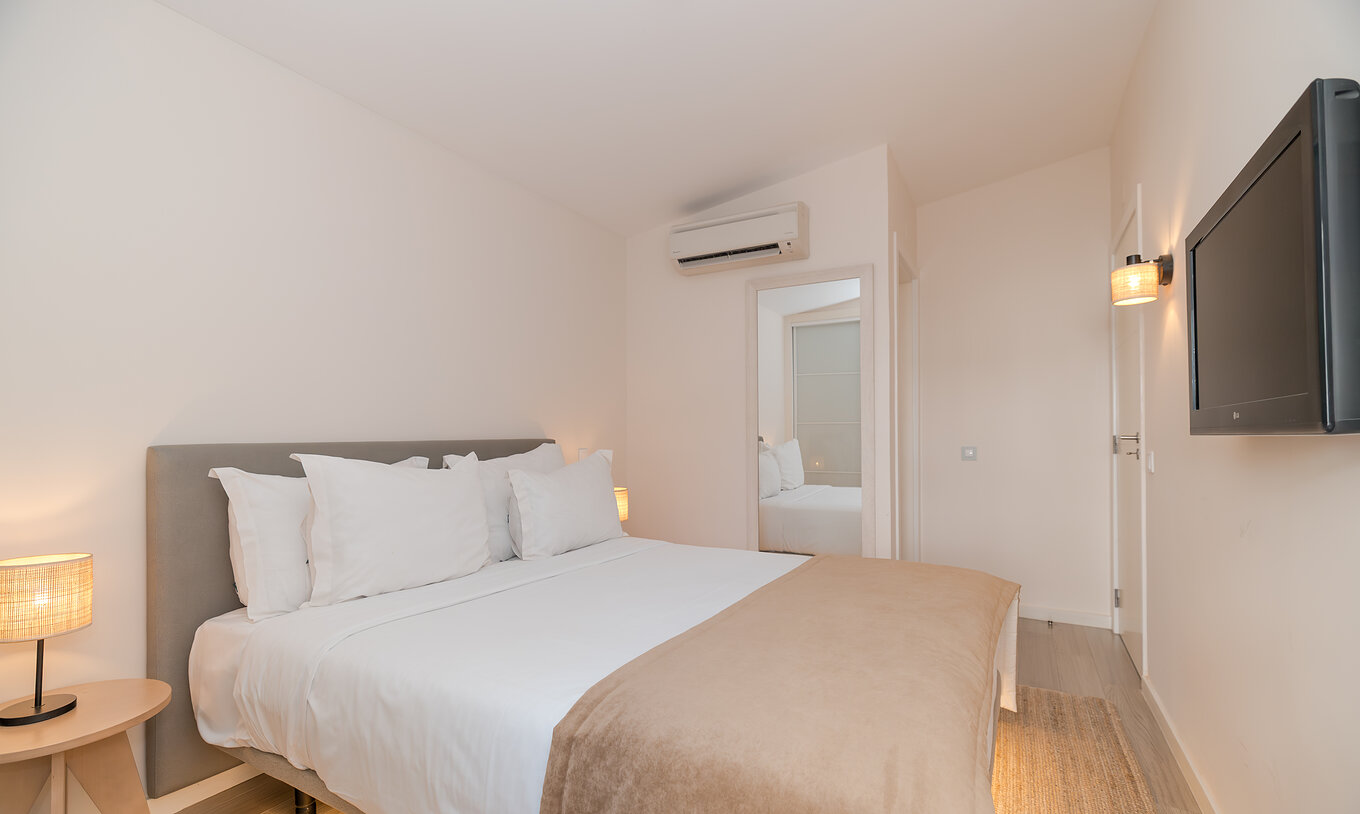 A Villa 2 Quartos Superior Vista Jardim do Pestana Alvor Beach Villas tem um quarto com cama de casal e televisão
