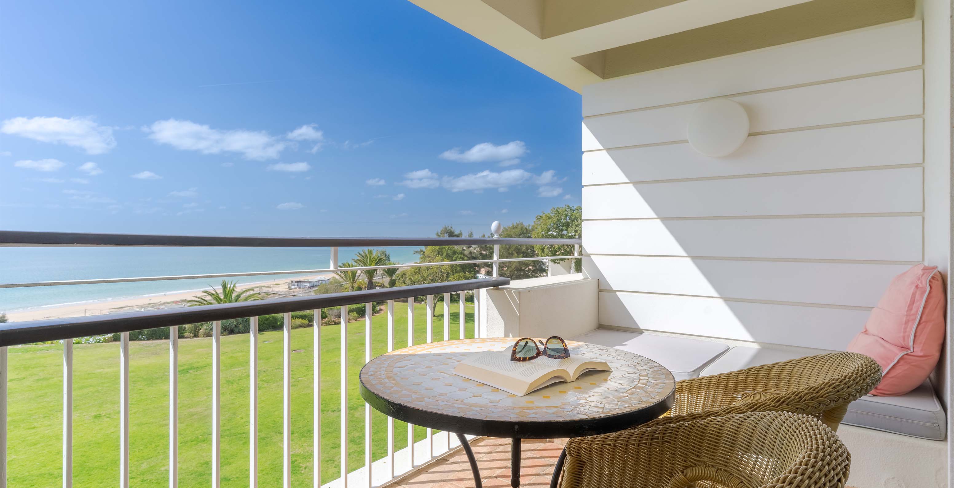 O Deluxe Vista Mar do Pestana Alvor Praia tem varanda com cadeiras, mesa e sofá com vista para o mar, praia e jardim do hotel