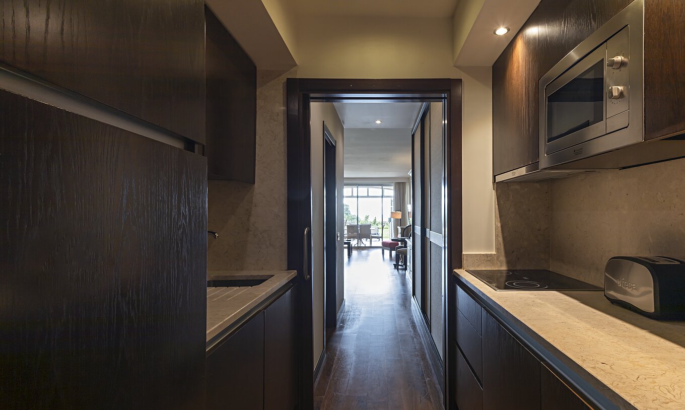 A Cliff Family do Pestana Alvor Praia tem uma cozinha equipada em madeira escura e pedra, com fogão e micro-ondas