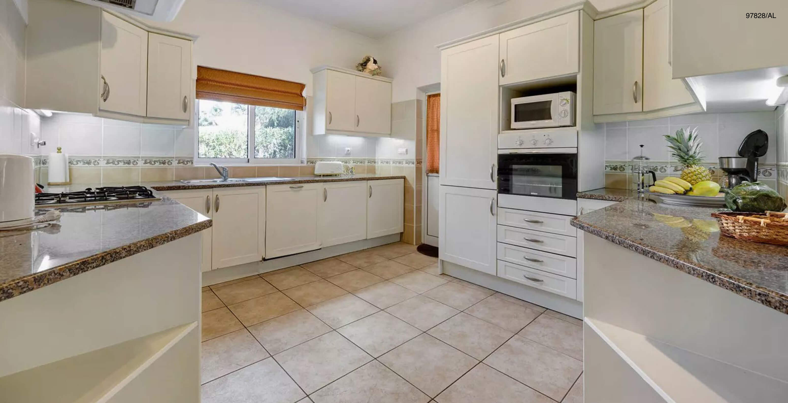 A Moradia V3 Standard do Pestana Carvoeiro Golfe tem uma cozinha equipada com armários brancos e eletrodomésticos