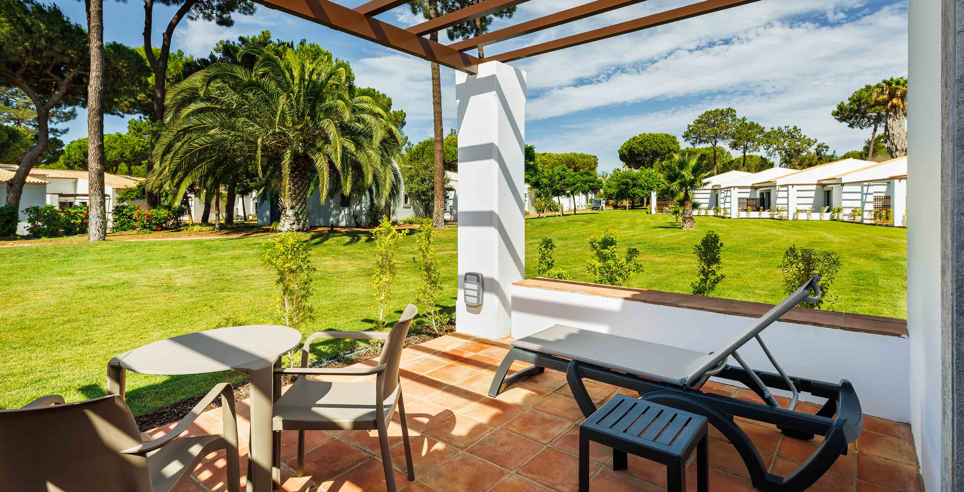 O Familiar Vista Jardim do Pestana Vila Sol - Vilamoura tem uma varanda com espreguiçadeira, mesa e vista para o jardim
