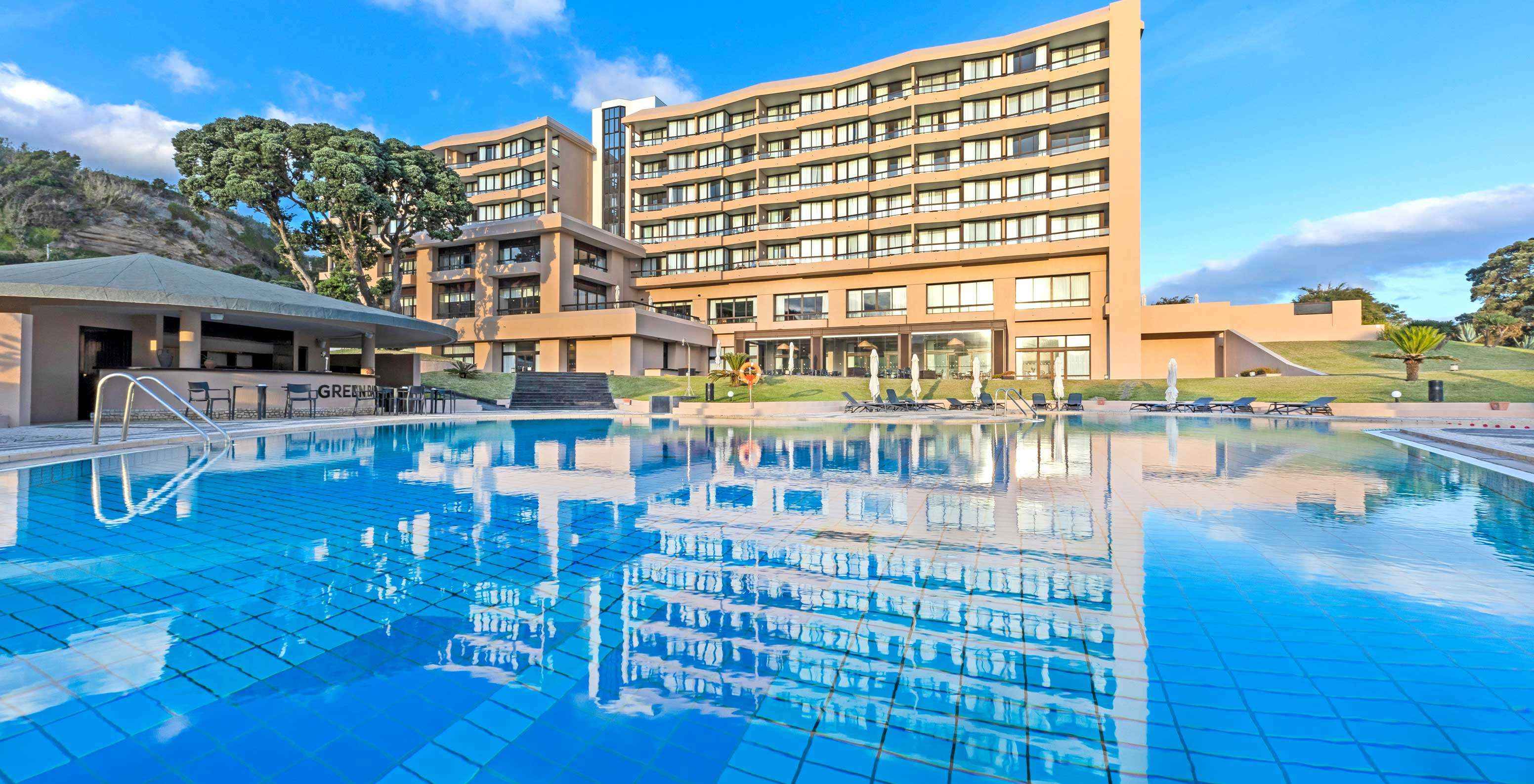 Piscina exterior no hotel de 4 estrelas, na Ilha de São Miguel, com vista para espreguiçadeiras e para o edifício principal