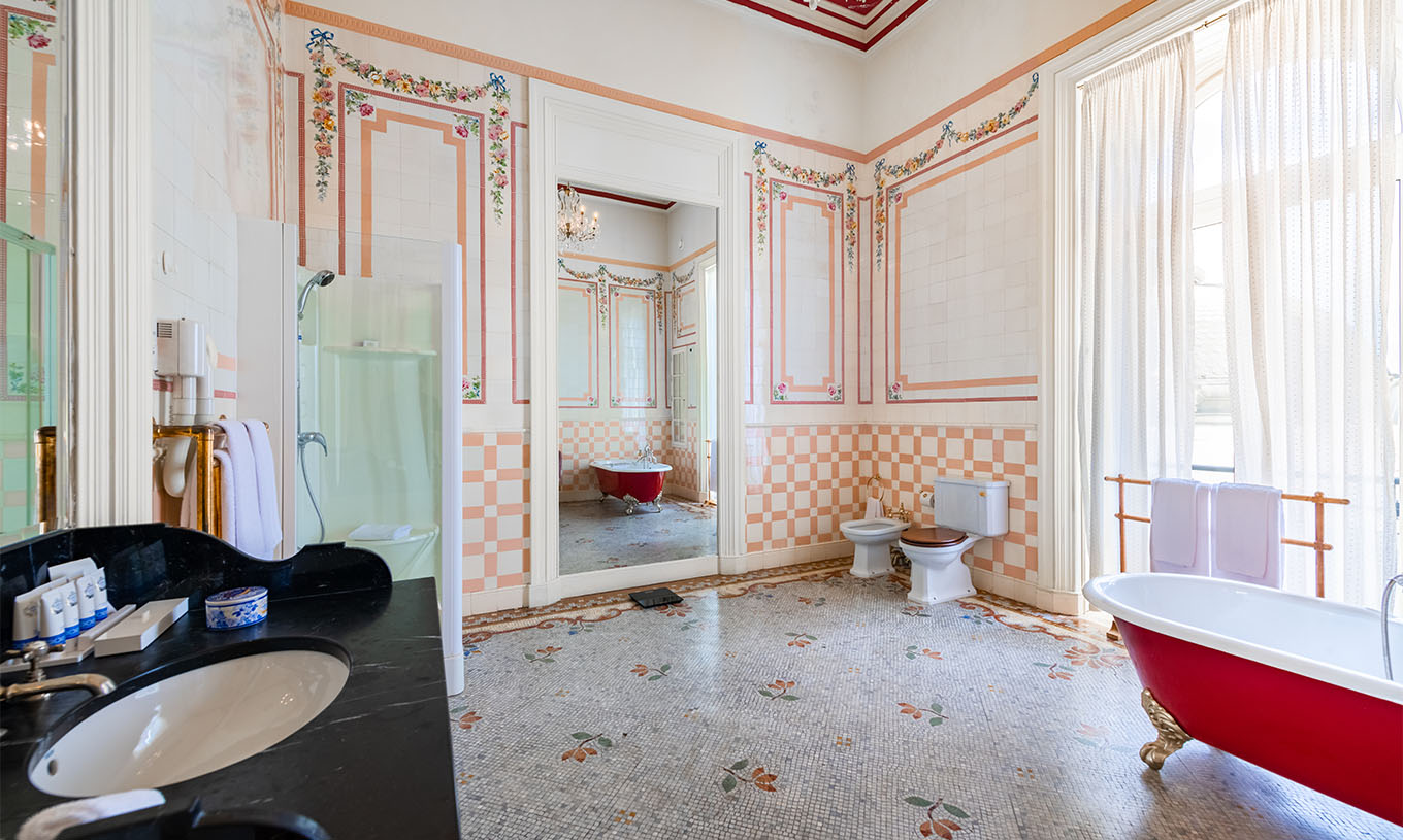 A Suite D. Amélia do Pestana Palace Lisboa tem uma casa de banho grande com azulejos, janela, banheira, duche e espelho