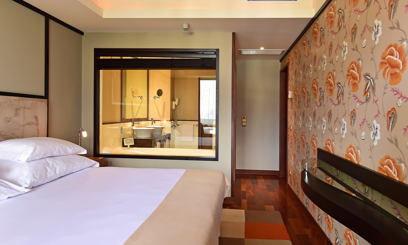 A Suite Presidencial do Pestana Casino Park tem uma cama de casal com vidro para a casa de banho e papel de parede a decorar