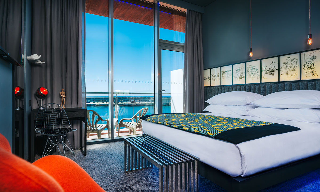 O Quarto CR Superior do Pestana CR7 Funchal tem uma varanda com ao lado da cama de casal, que tem duas cadeiras e vista mar