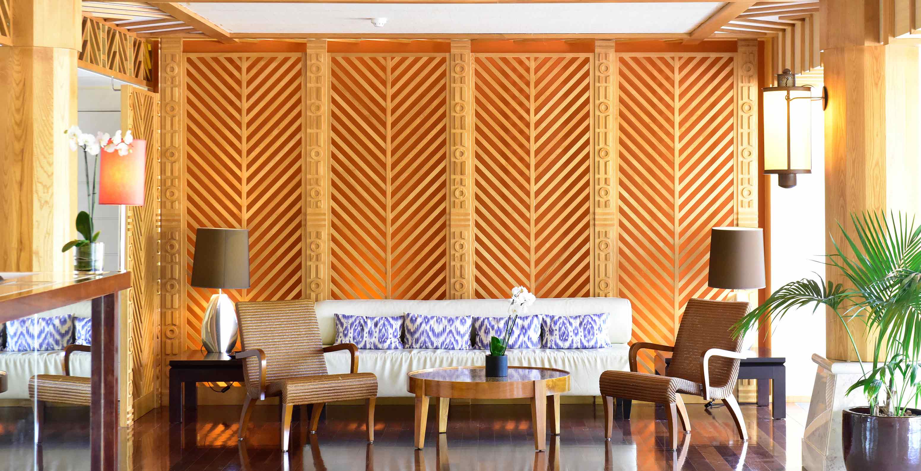 Sofá com almofadas, cadeirões e mesa de centro numa área de estar com decoração em madeira no Pestana Porto Santo