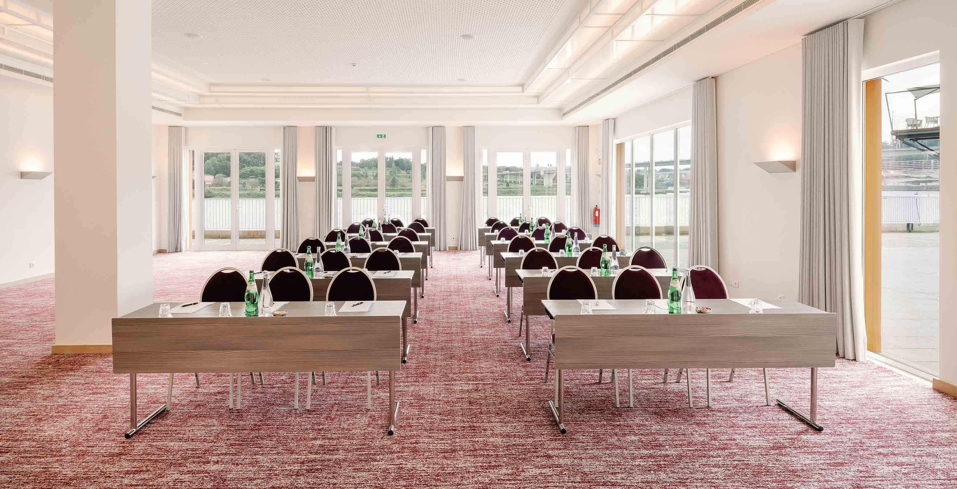 Sala Douro V com mesas, cadeiras e janelas grandes no Pestana Douro Riverside, Hotel com Piscina em Frente ao Rio Douro