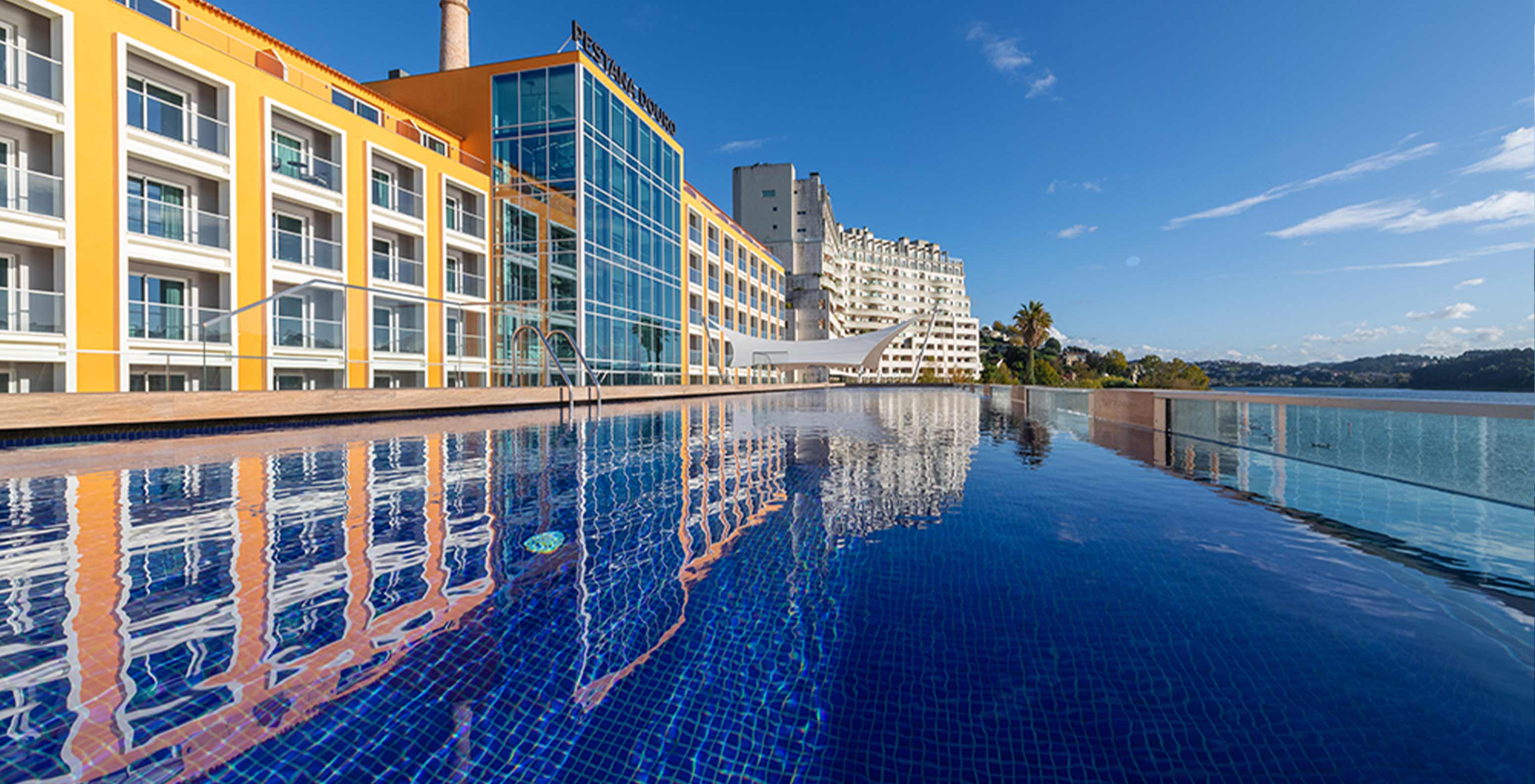 Vista exterior da fachada do Pestana Douro Riverside, com uma piscina à beira do rio Douro