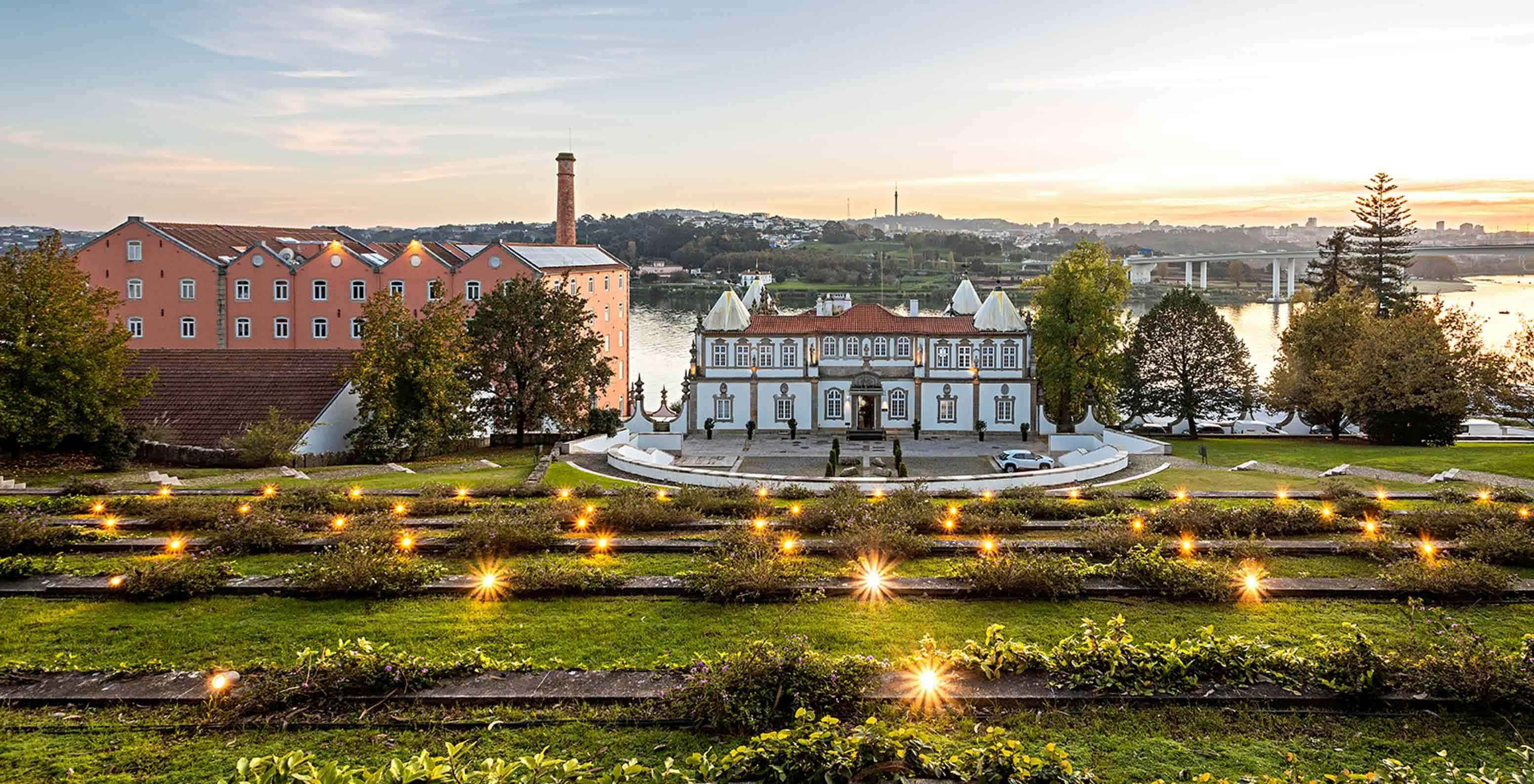 Vista exterior da fachada do Pestana Palácio do Freixo, rodeado de jardins e com vista para o rio Douro ao pôr do sol