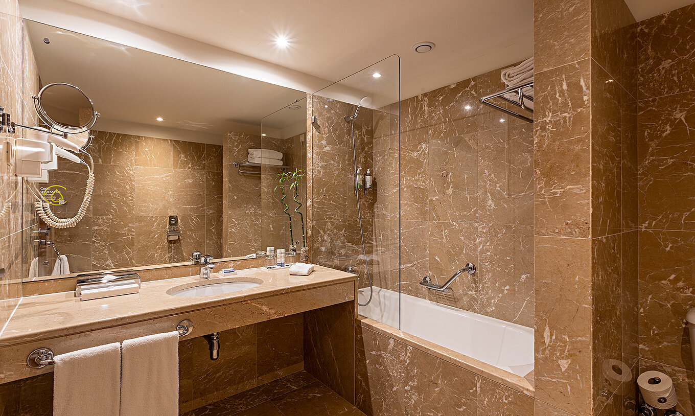 A Suite Grand View do Pestana Vintage Porto tem uma casa de banho com paredes de mámore castanho e uma banheira 