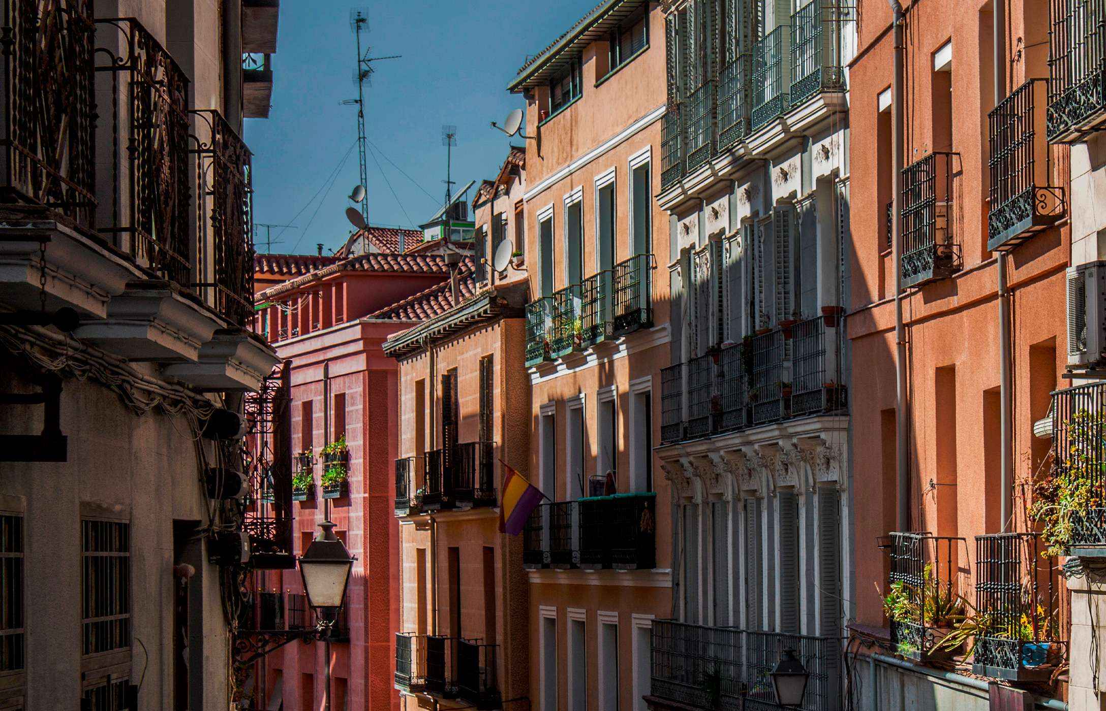Rua da zona histórica de Madrid, em Espanha com os edifícios tradicionais coloridos, com varandas e com plantas