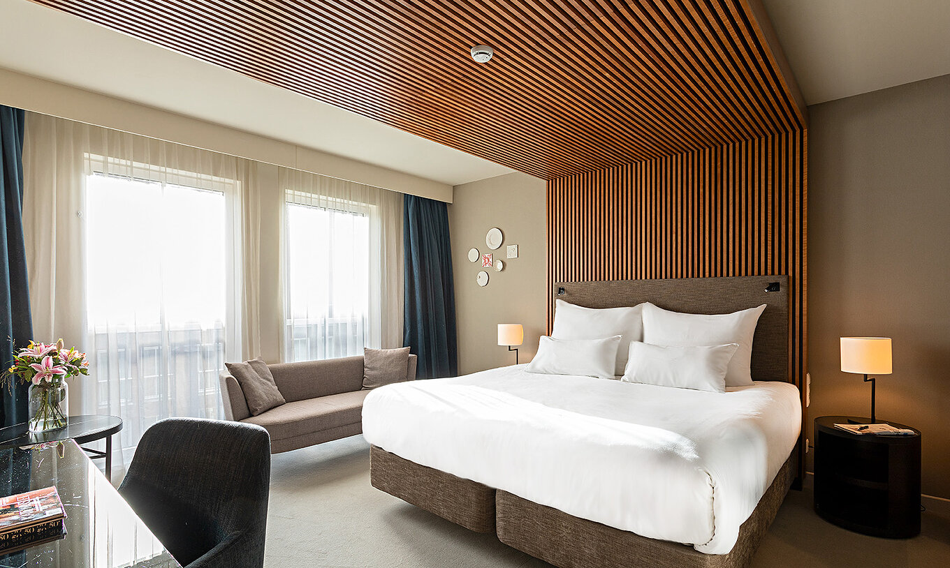 O quarto Executive do Pestana Amsterdam Riverside tem uma cama de casal, um sofá, e mesa de cabeceira com candeeiro