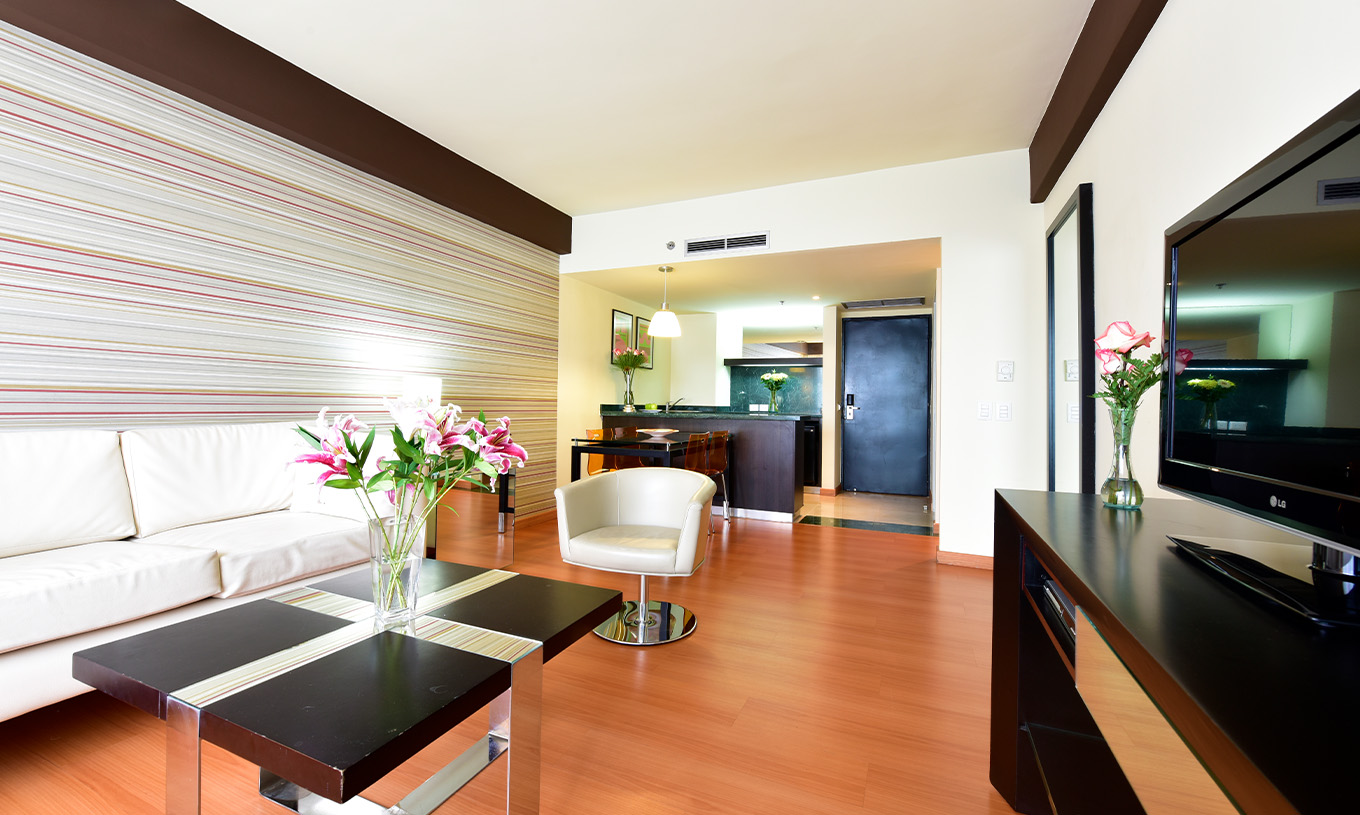 A King Junior Suite do Pestana Caracas tem uma sala com um sofá branco confortável, uma mesa de apoio e uma televisão