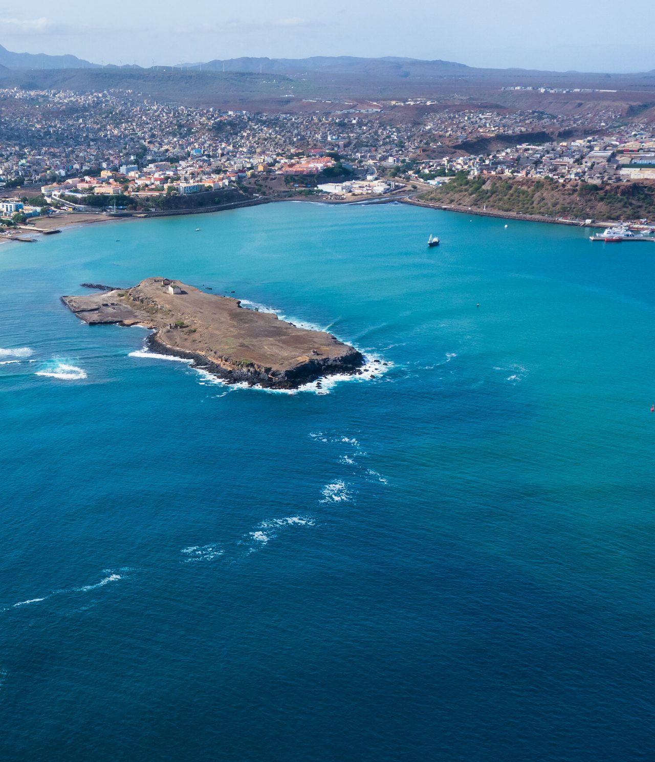  Luftaufnahme der Stadt Praia im Kontrast zwischen blauem Ozean und bunter Stadtlandschaft