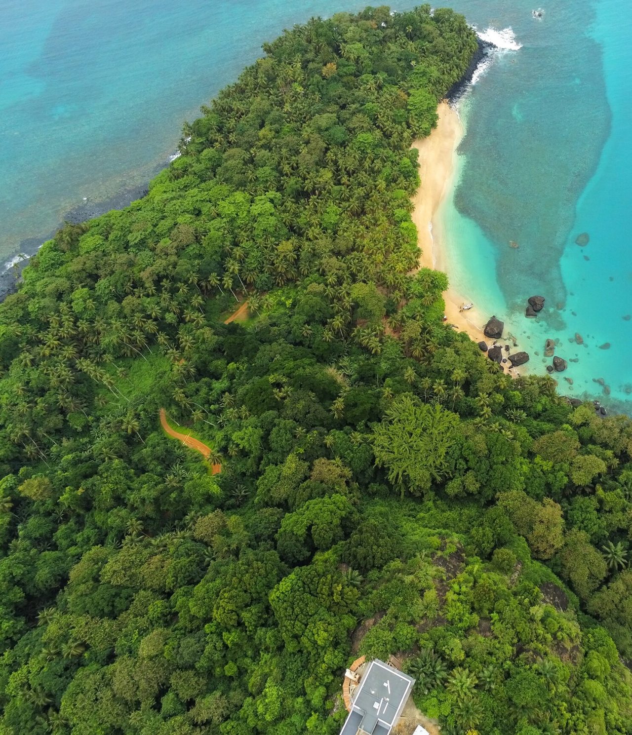 Luftaufnahme der Insel São Tomé und Príncipe, mit üppiger Vegetation, einem weißen Sandstrand und kristallklarem Wasser