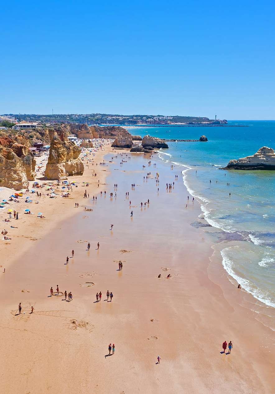 Besuchen Sie den Praia da Rocha mit vielen Felsen, die ins blaue Wasser der Algarve führen