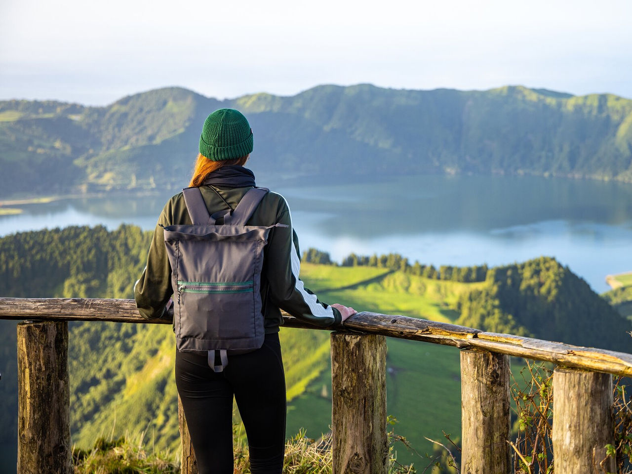 Person, die auf einem Pfad geht und den ruhigen Blick auf eine Lagune bewundert, die von Hügeln und Vegetation umgeben ist
